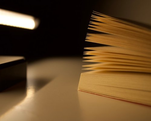 Cozy reading environment with a warm desk lamp casting soft light on a book